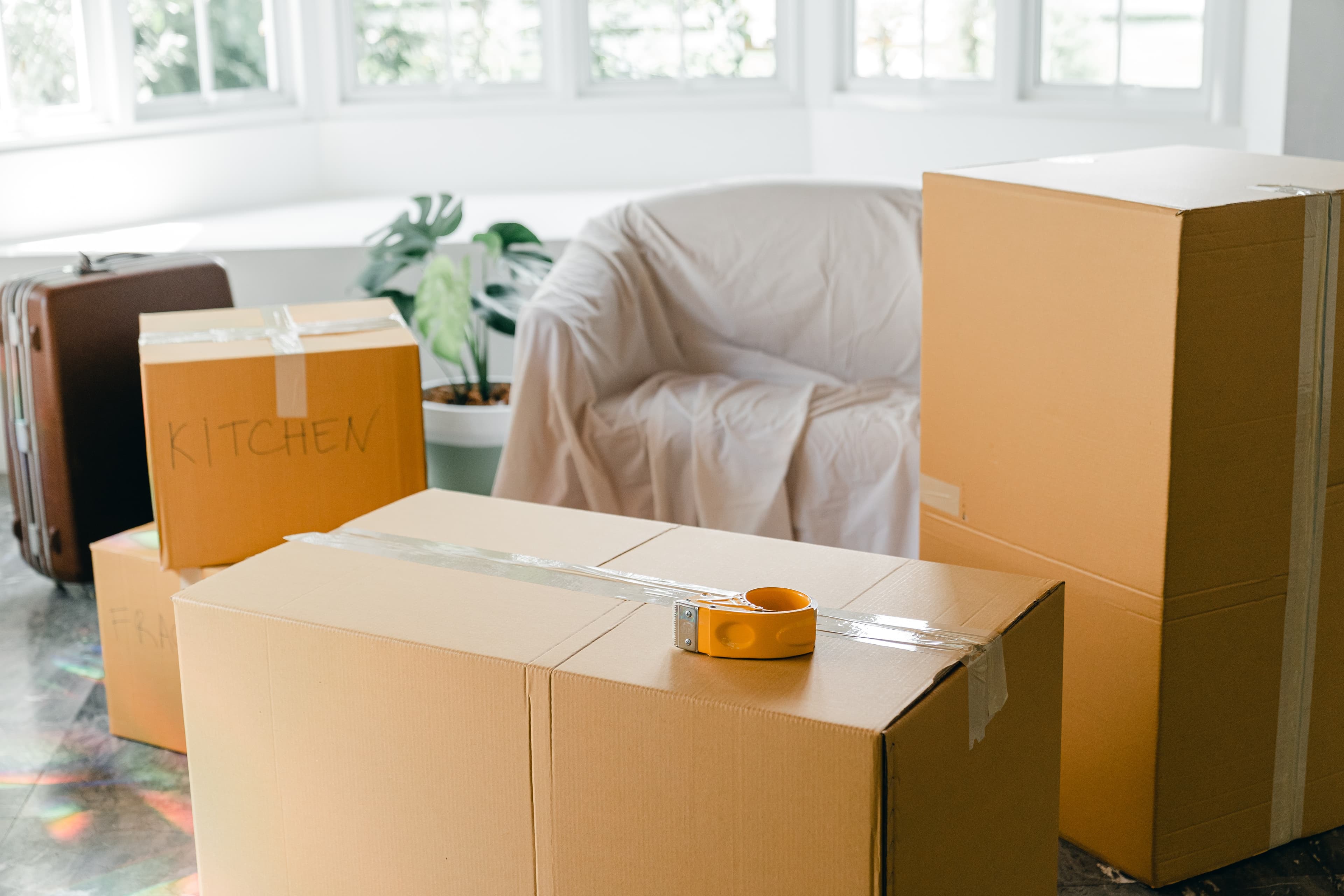 Umzugskartons und ein abgedecktes Sofa, das für einen Umzug vorbereitet wurde