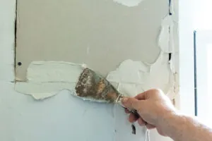 Spachtelmasse wird in dicken Schichten mit einem Spachtel auf eine Wand aufgetragen.