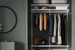 Einbauschrank vor grüner Wand mit Kleiderstange und Regalböden